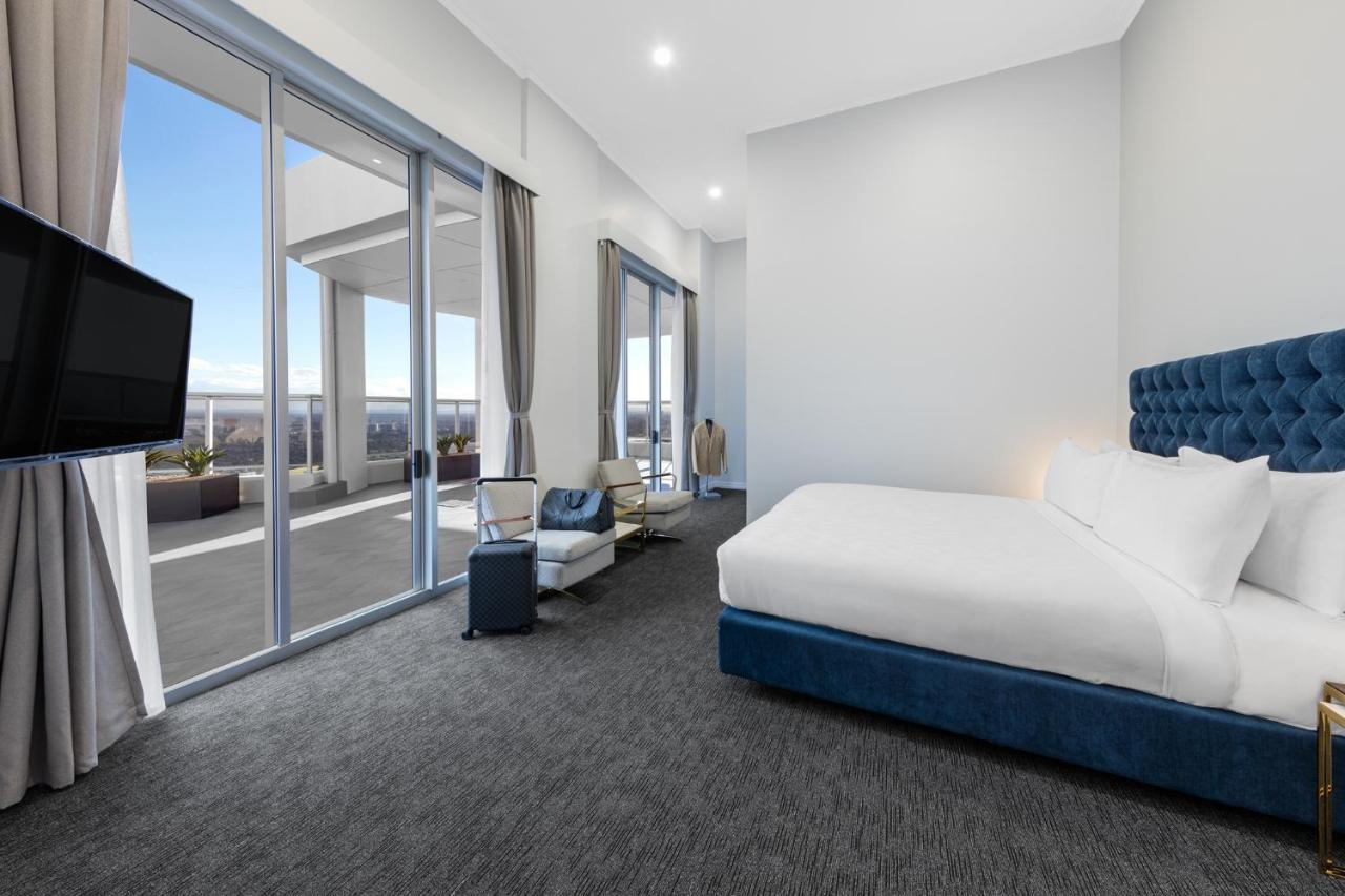 邦迪交界处美利通公寓式酒店 悉尼 外观 照片 The photo shows a modern and spacious hotel room. It features a large bed with a blue headboard, a flat-screen TV mounted on the wall, and a cozy seating area with a chair and small table. The room has large windows that offer natural light and a vie