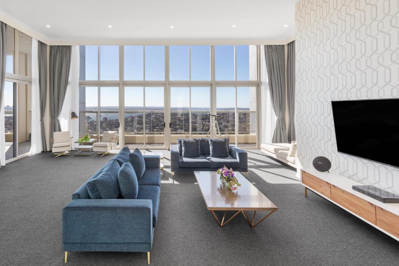 邦迪交界处美利通公寓式酒店 悉尼 外观 照片 The photo shows a modern and spacious living area. It features large windows that provide a panoramic view of the outside landscape and allow natural light to fill the room. The interior design includes a blue sectional sofa placed in the center, com