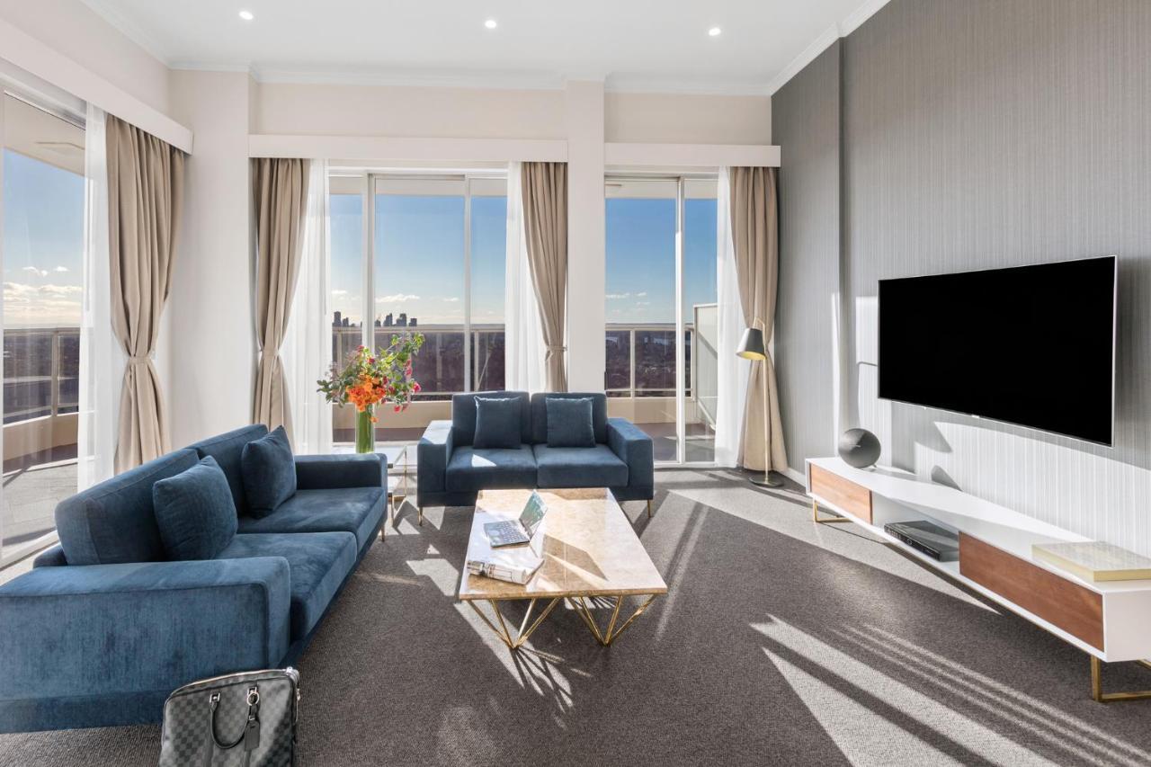 邦迪交界处美利通公寓式酒店 悉尼 外观 照片 The photo depicts a modern living room with a stylish and contemporary design. It features a cozy seating arrangement with a blue sofa and two matching armchairs. In front of the seating area is a coffee table with a geometric design. The room has la